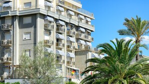 A multi-story residential building with balconies, a flag, and palm trees. - Hotel Residence Villa Jolanda (Camaiore)