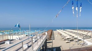 A deck with sun loungers and umbrellas, a pool, and a view of the sea. - Hotel Residence Villa Jolanda (Camaiore)
