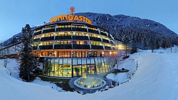 Un hotel moderno con diseño circular, una bañera de hidromasaje visible y un telesilla al fondo.