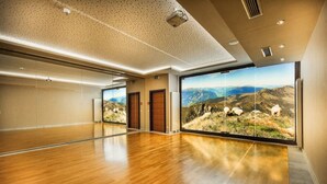 Una habitación amplia con piso de madera, ventanas grandes con vista a la montaña y un techo con un diseño moteado.