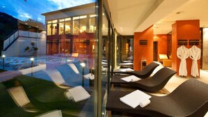 Un spa moderno con paredes de vidrio, sillones de descanso y una zona de piscina a la vista.