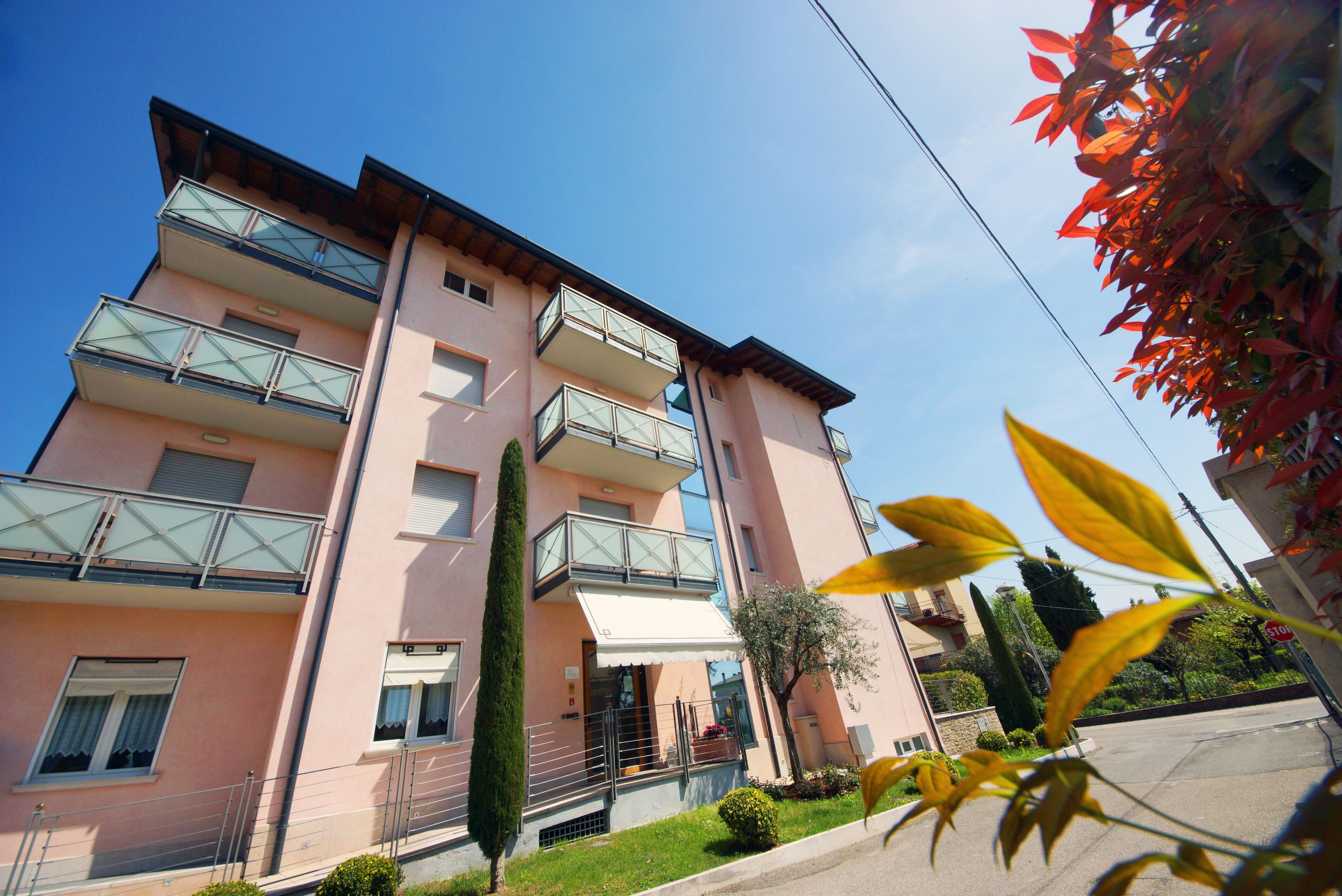 Un immeuble résidentiel à plusieurs étages, doté de balcons, d’une entrée bien visible et surplombant un ciel dégagé.