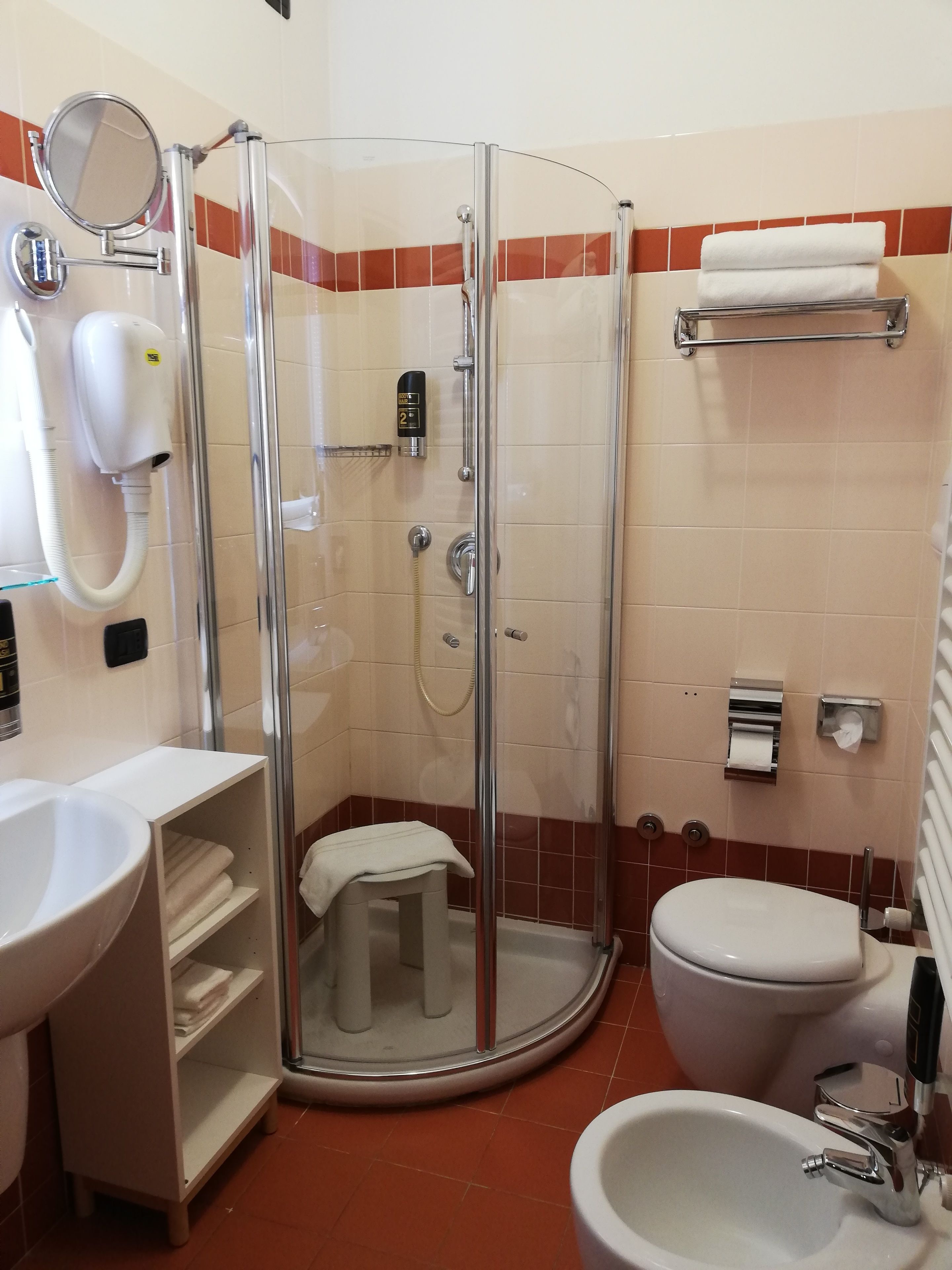 A bathroom with a glass-enclosed shower, a toilet, a sink, and a towel rack.