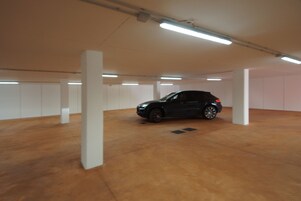 Un estacionamiento con un coche negro aparcado en el centro.