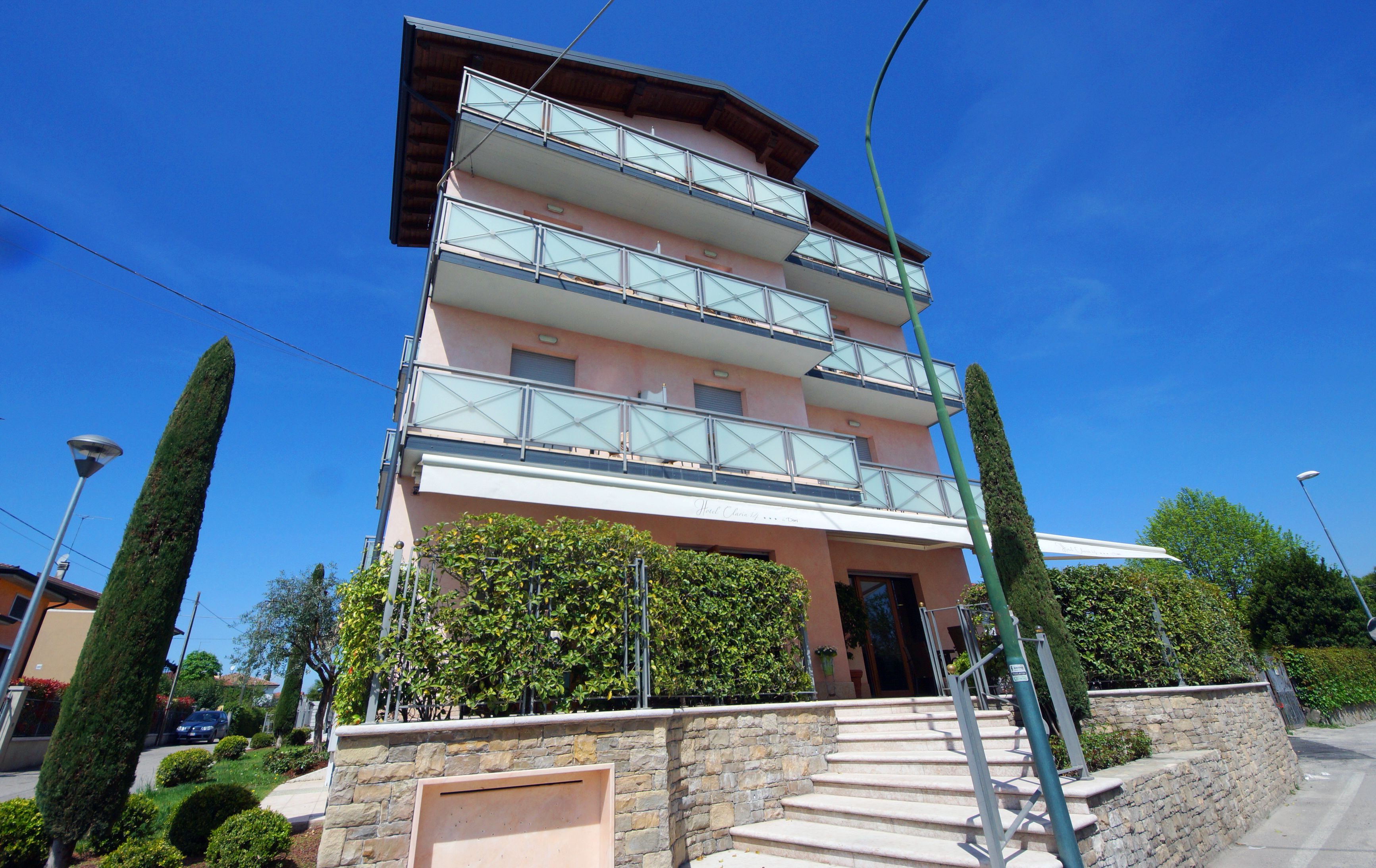 Un hotel de varios pisos con fachada de piedra, balcones y un cielo azul despejado.