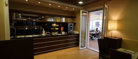 Un hall d’hôtel comprenant un espace buffet, des sièges et une vue sur l’extérieur.