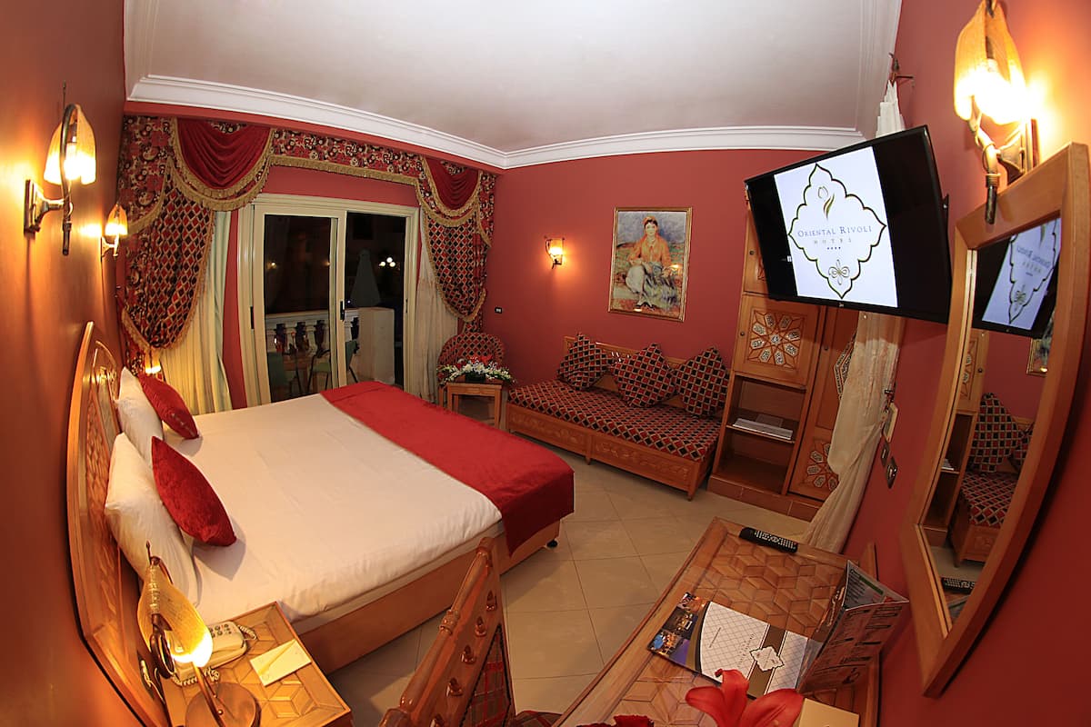 Ein Hotelzimmer mit einem großen Bett, einer Sitzecke, einem Schreibtisch mit Computer und einem Fernseher.