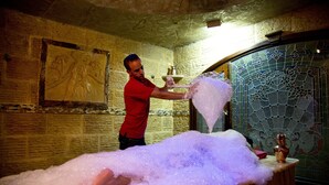 A person in a red shirt pouring a large amount of bubble bath into a bathtub. - Oriental Rivoli Hotel & SPA (Sharm El Sheikh)