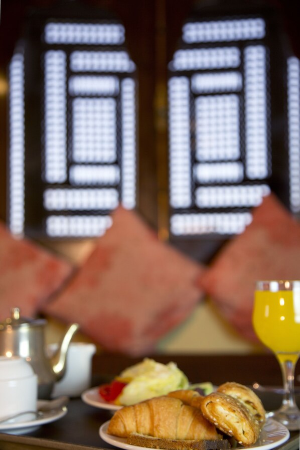 A breakfast table with croissants, fruit, and a glass of orange juice.