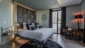 A modern bedroom with a large bed, a wall clock, and a small seating area with a table and chairs. - A Casa Di Mà (Lumio)