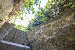 Un conjunt d'escales de pedra que s'eleven per un camí rocós, envoltat de vegetació i arbres.