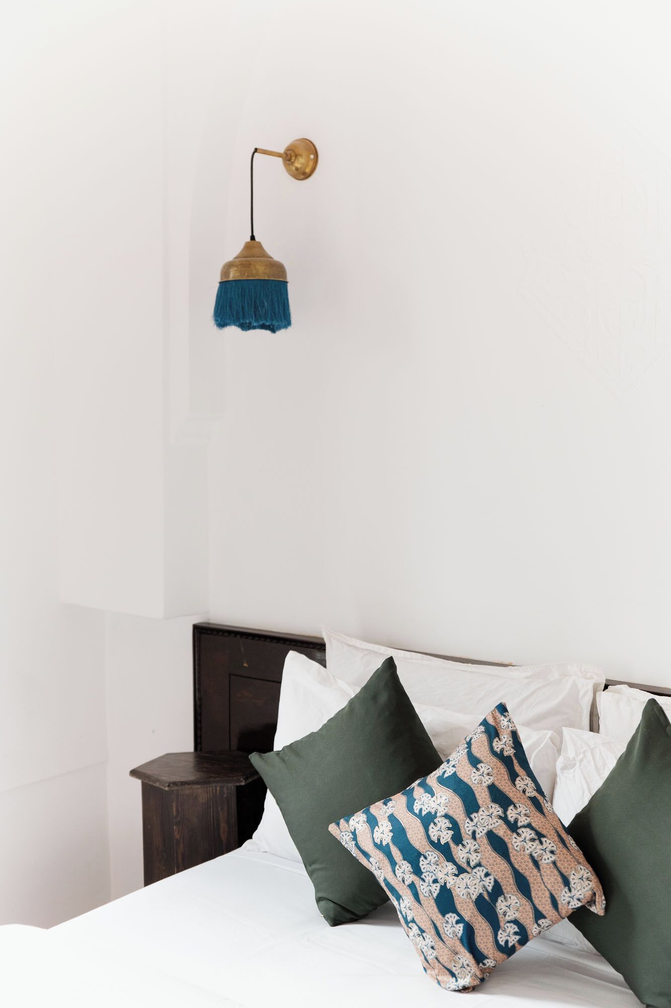 A bedroom with a bed, a bedside table, and a wall-mounted lamp.