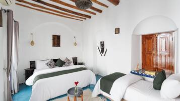 Un dormitorio con una cama grande, un sofá más pequeño, techo de madera y una puerta de madera.