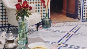A dining table set with plates, bowls, and a vase of red roses. - Riad Twilight (Marrakech)