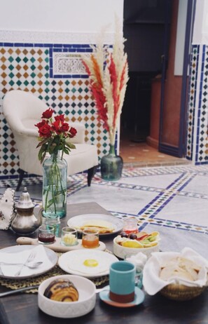 A dining table set with plates, bowls, and a vase of red roses.