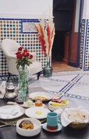 Una mesa de comedor dispuesta con platos, tazones y un jarrón de rosas rojas.