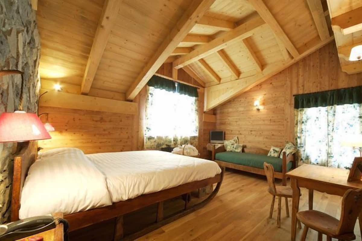 A cozy log cabin room with a bed, a desk, and a chair.