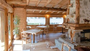 Un interior rústico de madera con comedor, chimenea y ventanas amplias.