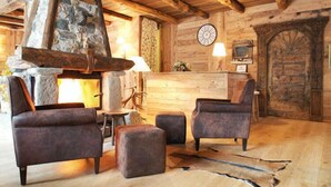 Un interior rústico con chimenea de piedra, paredes de madera, un reloj y sillones de cuero.