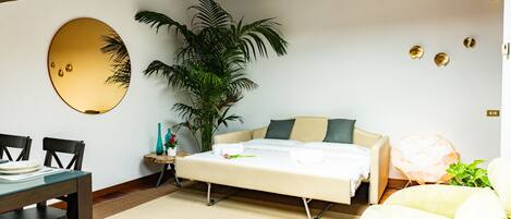 A compact bedroom with a bed, bedside table, and a large potted plant.