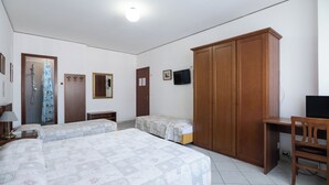 Un dormitorio con dos camas, un armario de madera, un escritorio, televisor y zona de ducha.