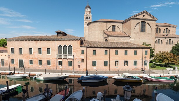 Un edificio histórico con una torre de campanas y una iglesia con ventanas de arco.