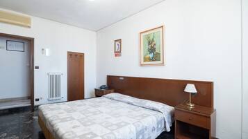 Una camera d'albergo con un letto, un comodino, una lampada e un quadro appeso al muro.
