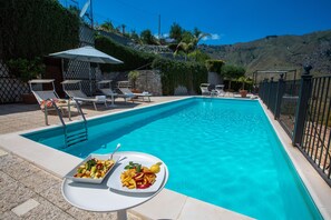 Ein Schwimmbecken mit Liegestühlen und einem Tisch mit Obst.