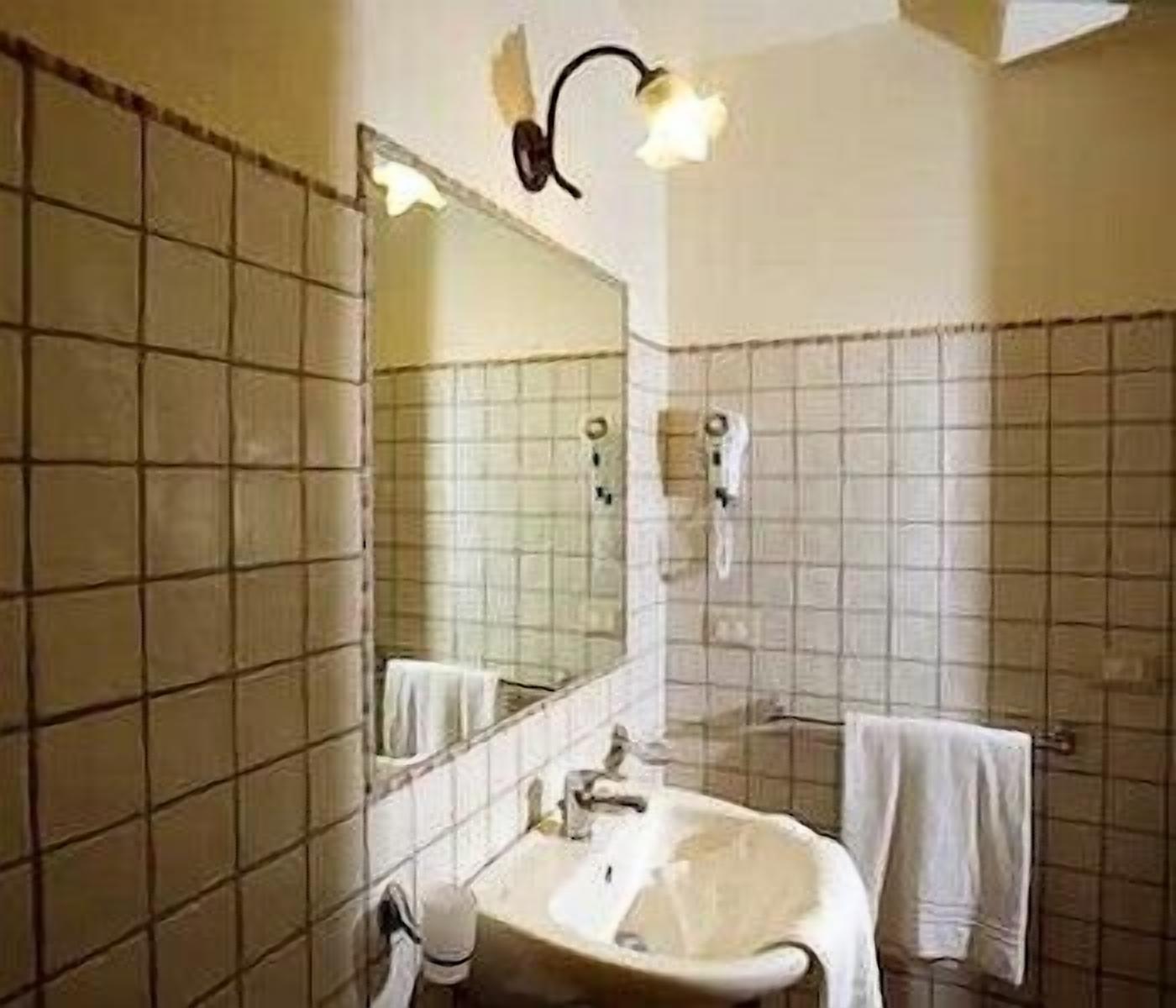 A bathroom with a sink, mirror, and towel rack.