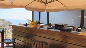 Een balkon met een houten leuning, een fruitmand en uitzicht op zee.