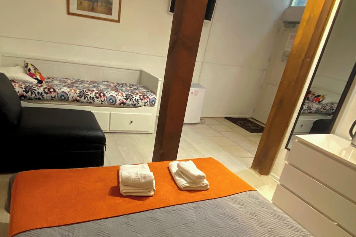 A hotel room with a bed, a chair, a small table, a mirror, and a picture on the wall.