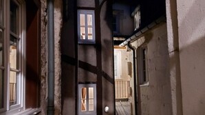 A narrow alleyway with buildings on either side, featuring multiple windows and a visible door. - Le Chambellan (Dijon)