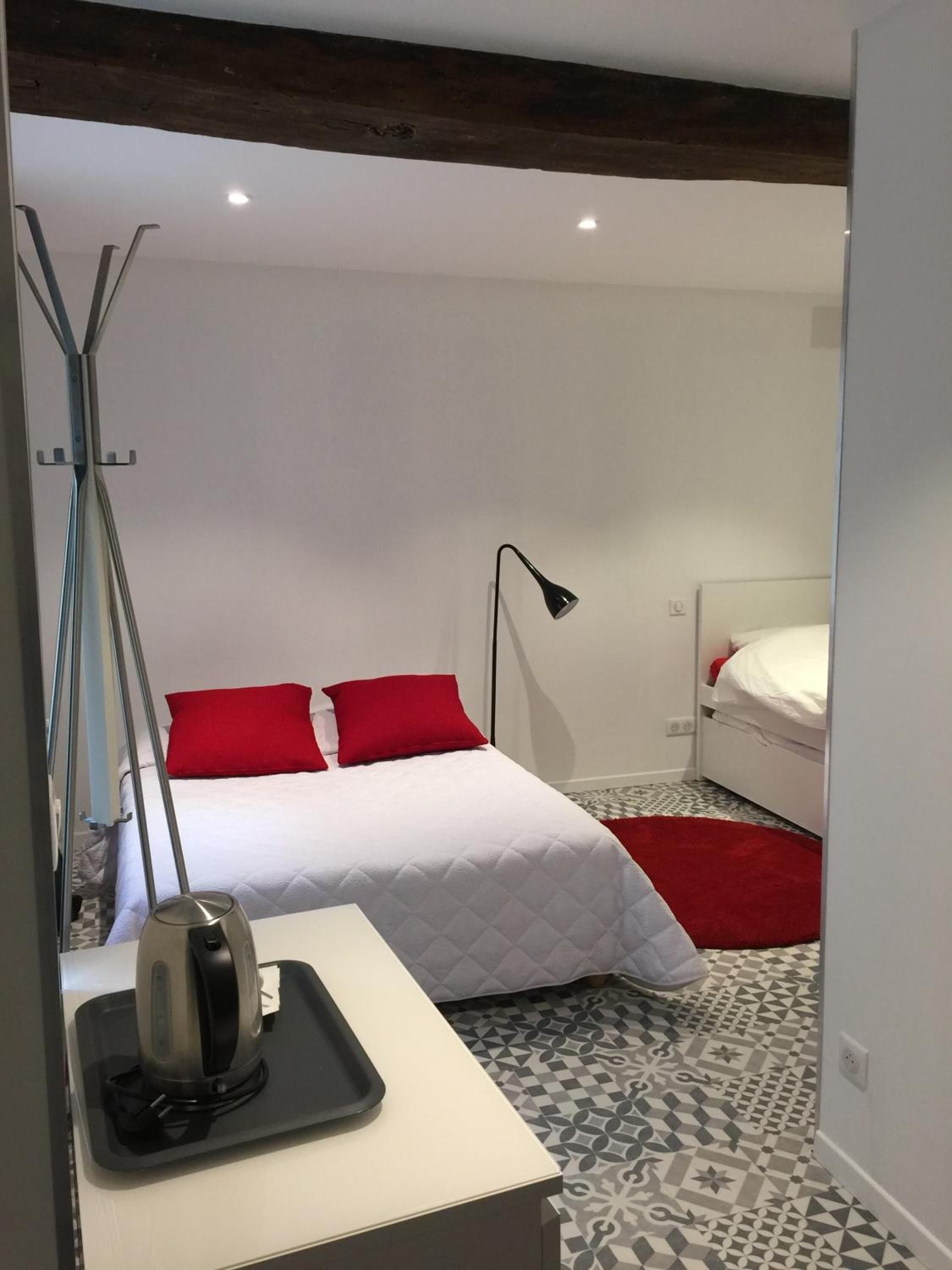 A modern bedroom with a bed, a desk, a chair, a lamp, and a red rug.