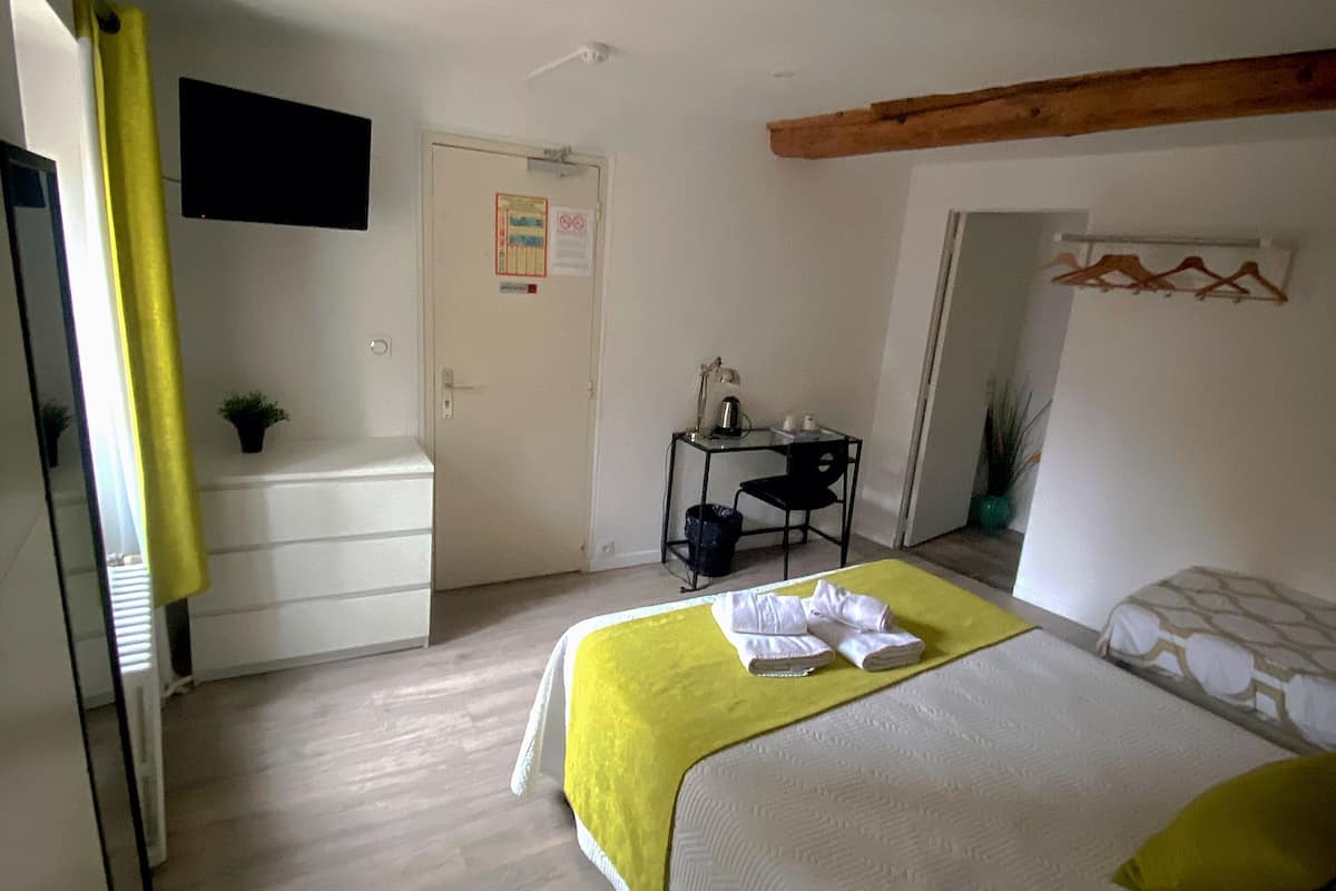 A bedroom with a bed, a desk, and a television.