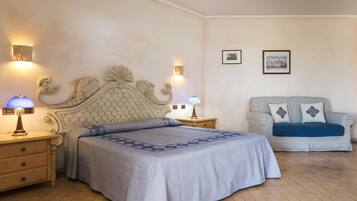 A bedroom with a bed, nightstands, a sofa, and wall-mounted lamps.