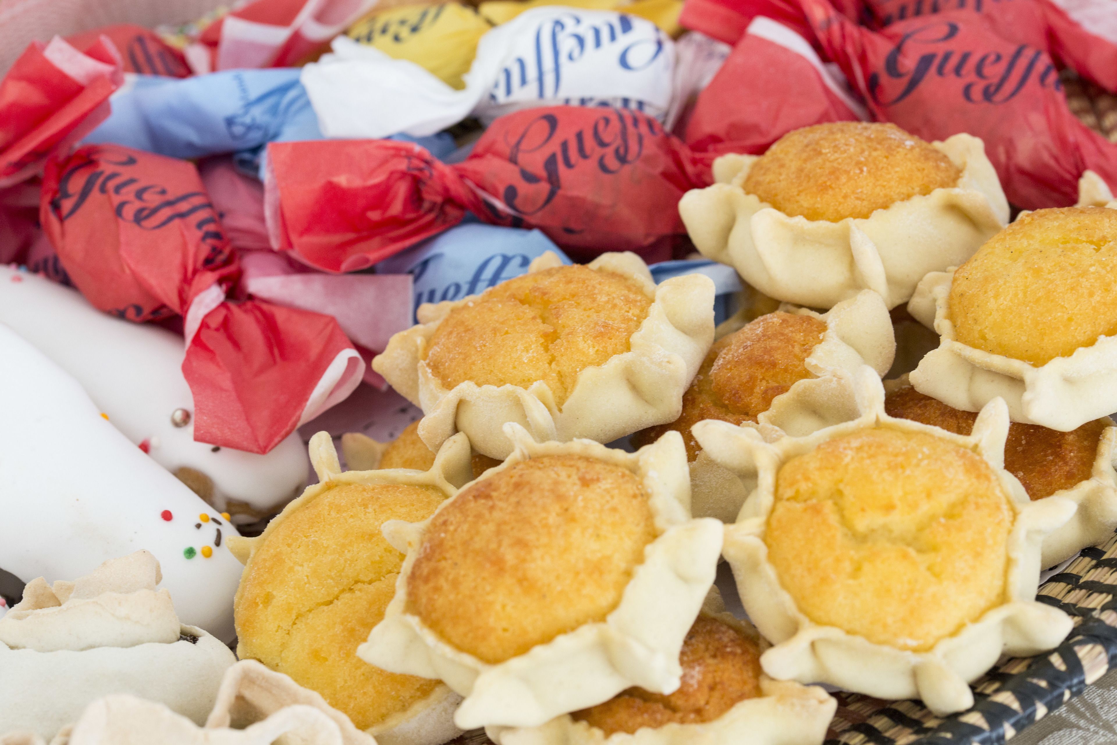 Un panier rempli de muffins dont les bords sont décorés de motifs ondulés, le tout entouré de divers emballages de couleurs différentes.