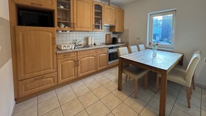 Una cocina con armarios de madera, una mesa de comedor, sillas y un ventanal con vistas.