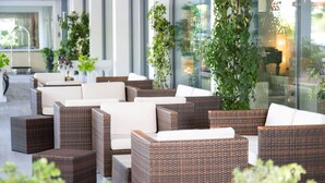 Un espacio exterior moderno con mobiliario de mimbre y plantas en macetas.
