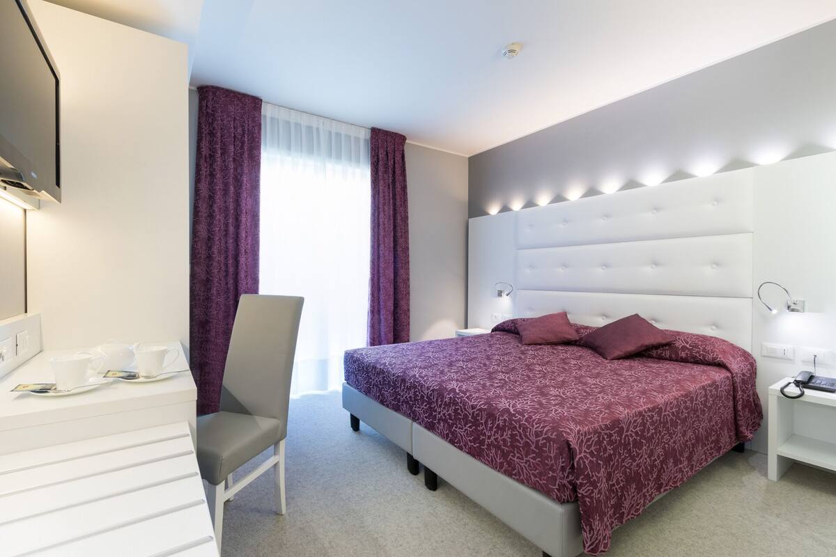 Une chambre d’hôtel moderne équipée d’un grand lit, d’un bureau avec une chaise et d’une télévision.