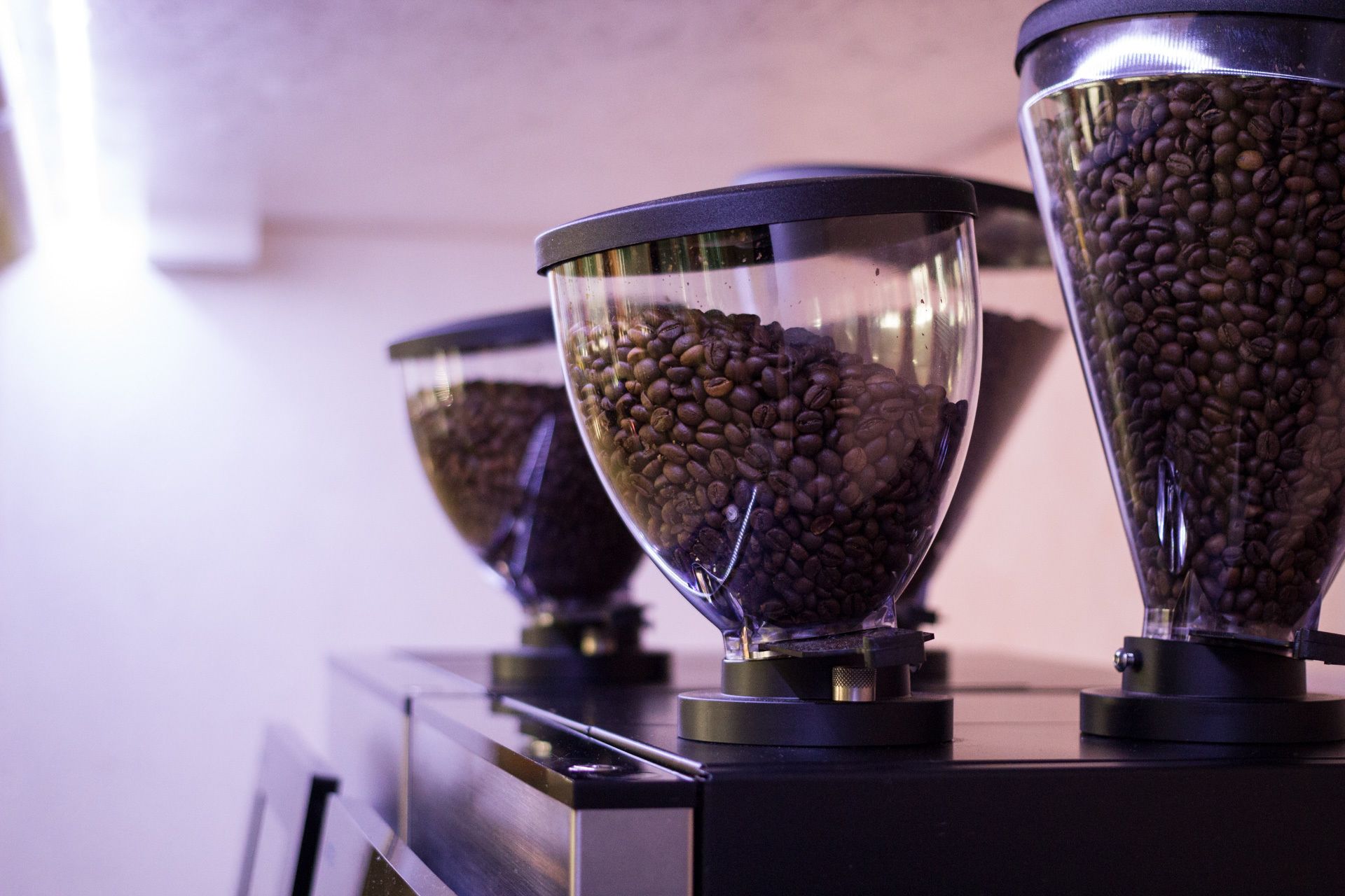 Drei Kaffeemühlen mit Kaffeebohnen darin.