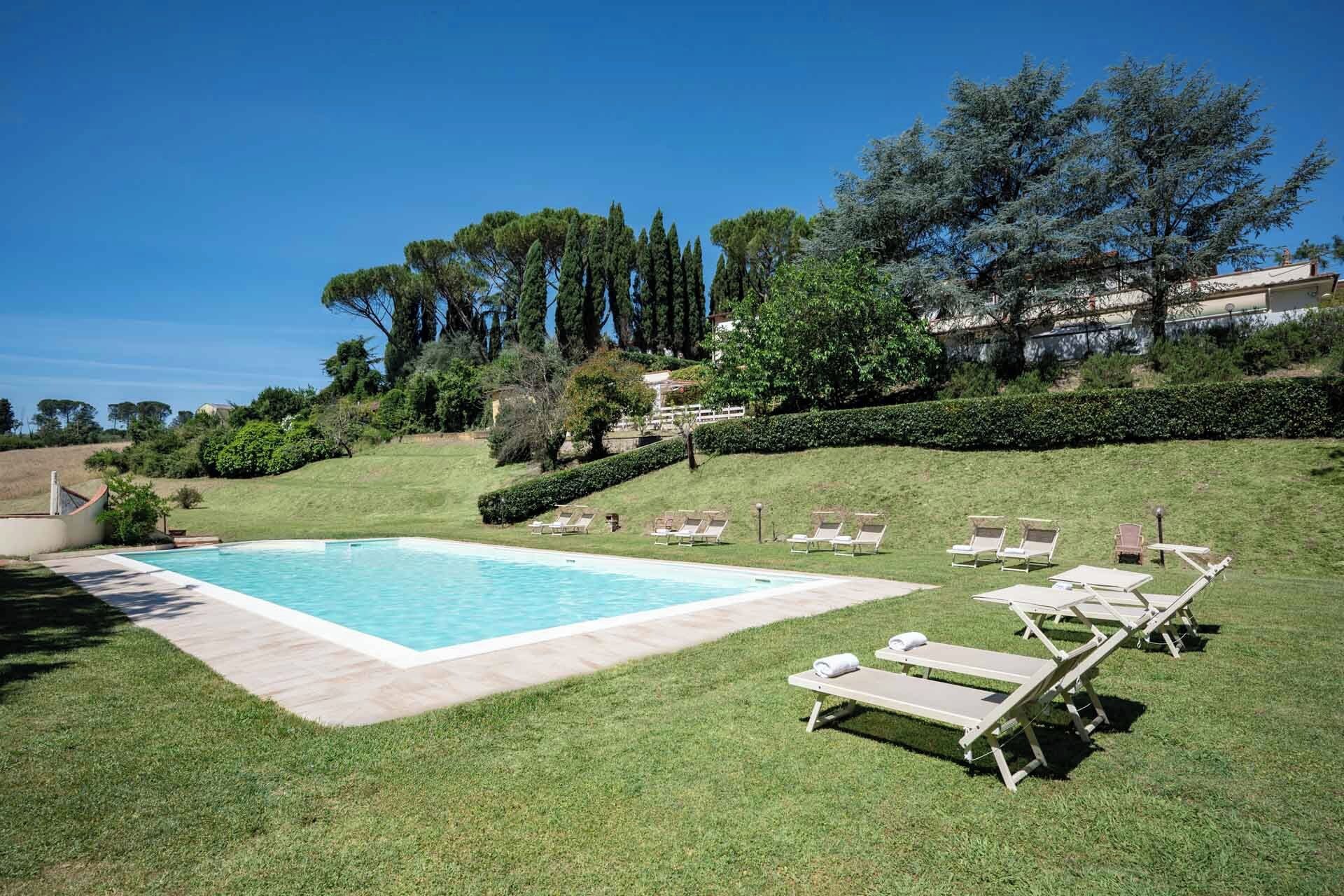 A swimming pool with lounge chairs and a grassy area.