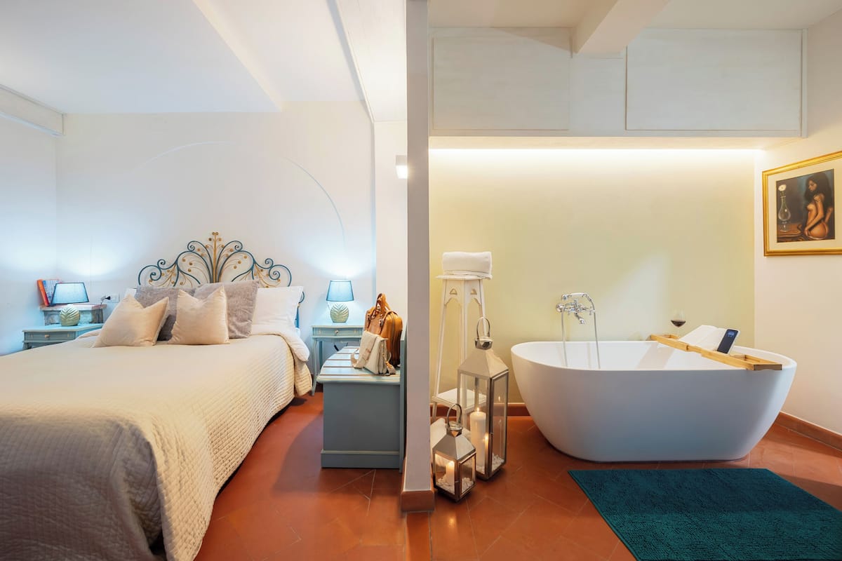 Een slaapkamer met een groot bed, nachtkastjes en een nachtkastje met een lamp.