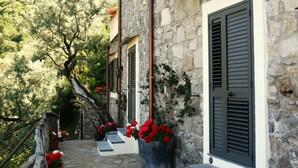 A stone building with a balcony, steps leading to a door, and potted plants. - Casarufolo Paradise (Sorrento)