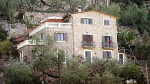 A stone building with multiple balconies, a staircase, and surrounding vegetation. - Casarufolo Paradise (Sorrento)