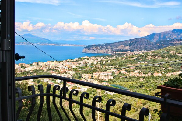Un balcone con vista su una cittadina costiera, montagne e mare.