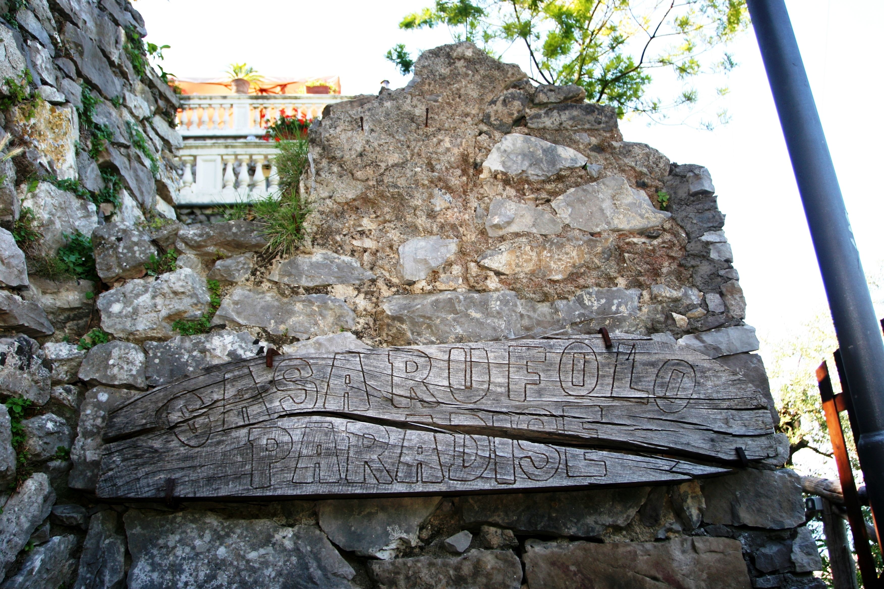A stone wall with a wooden sign that reads "CARUFO PARADISE".