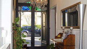 A hallway with a chandelier, a mirror, a wooden dresser, and a blue chair. - La Mimosa Bed and Breakfast (Lucca)