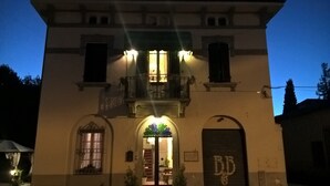 A building with a balcony, a door with a sign, and a window with a curtain. - La Mimosa Bed and Breakfast (Lucca)