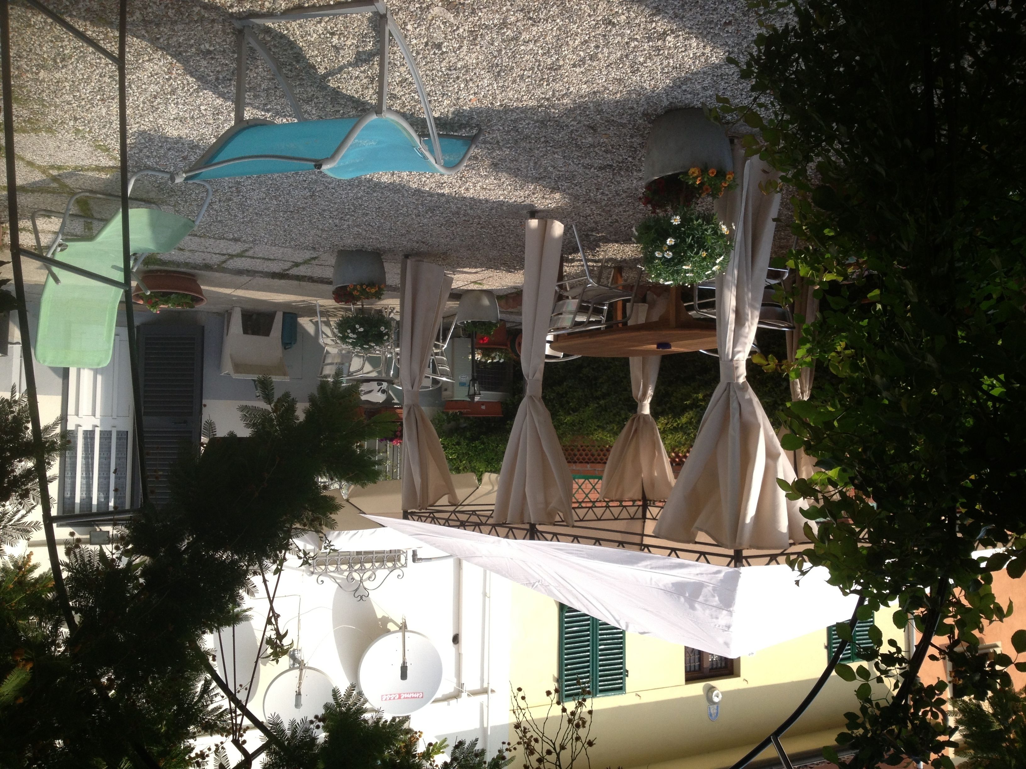 A terrace with outdoor seating, a water feature, and a view of a building with a balcony.