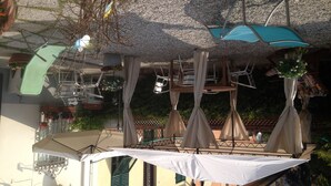 A rooftop terrace with multiple umbrellas, chairs, and hanging planters. - La Mimosa Bed and Breakfast (Lucca)